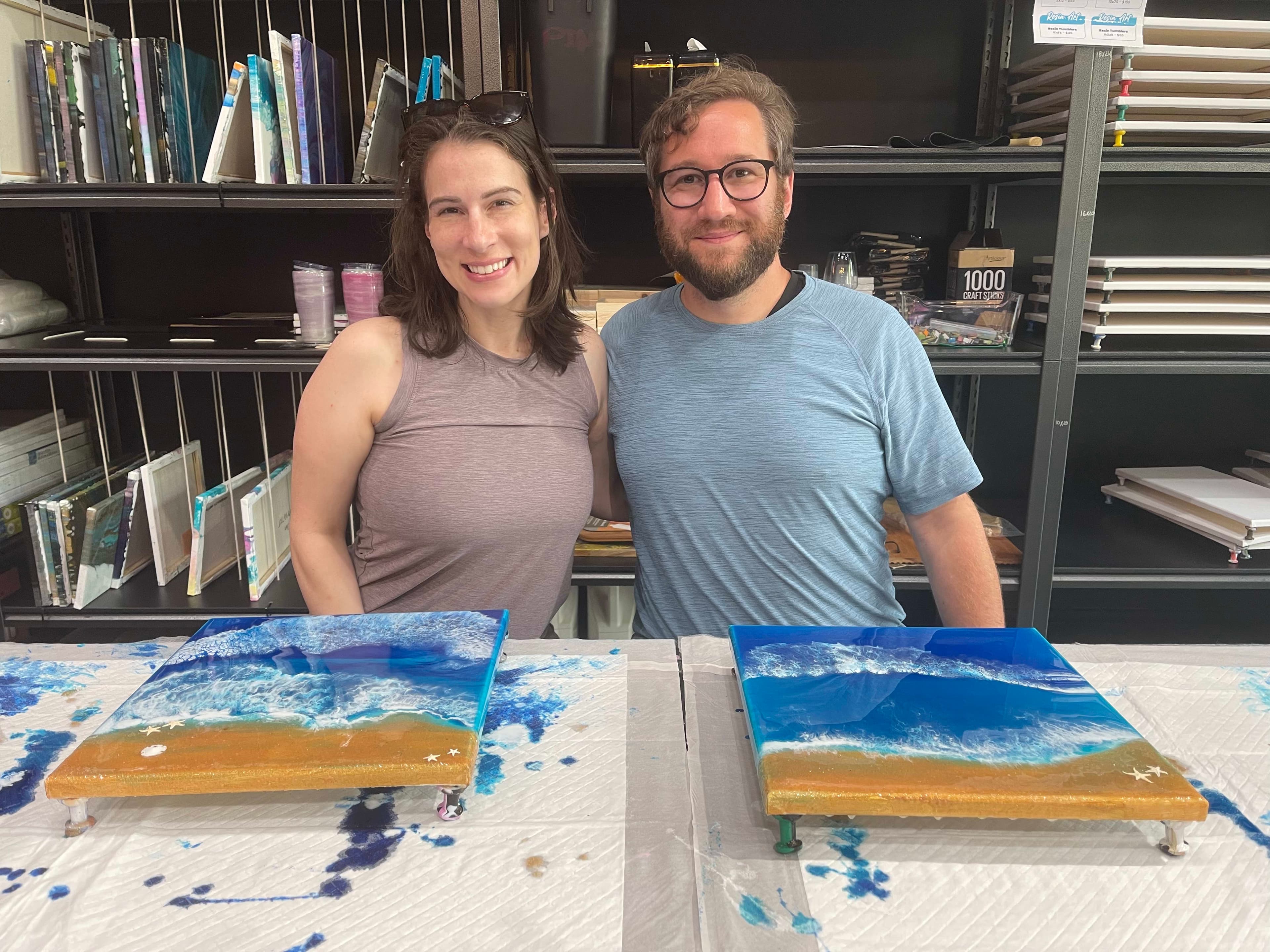 A couple admiring their finished resin beach scene canvas at ATL Fluid Art
