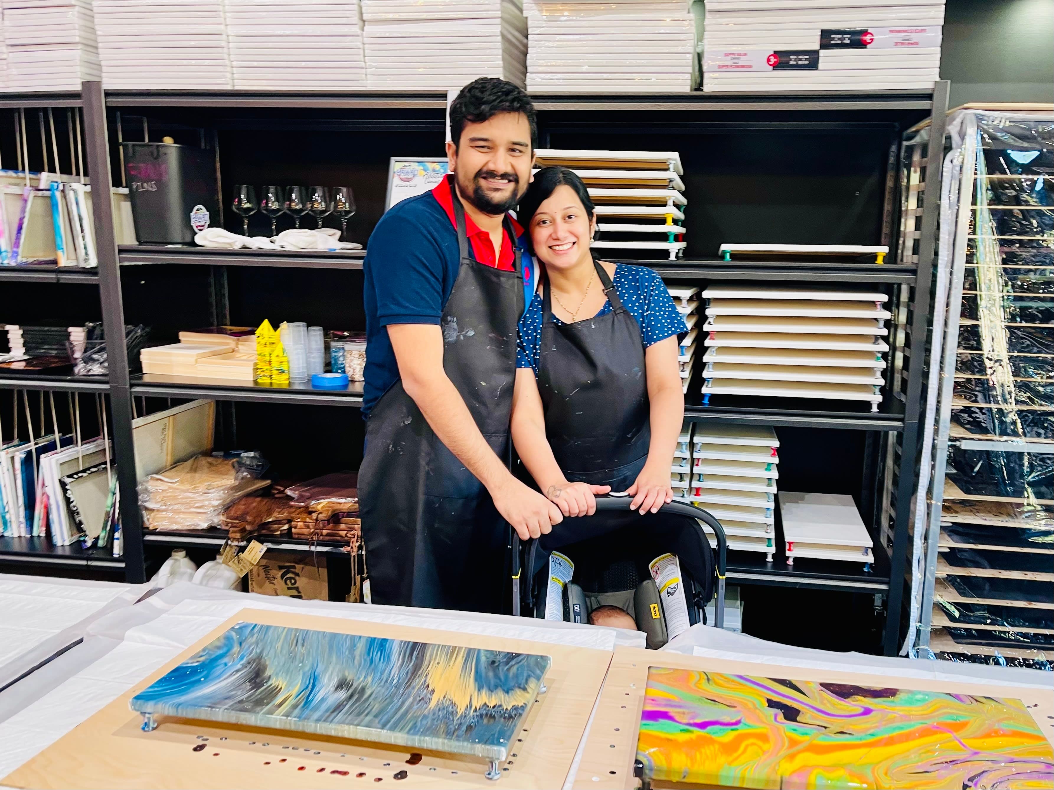 A couple sipping wine and admiring their finished fluid art canvases on date night at ATL Fluid Art